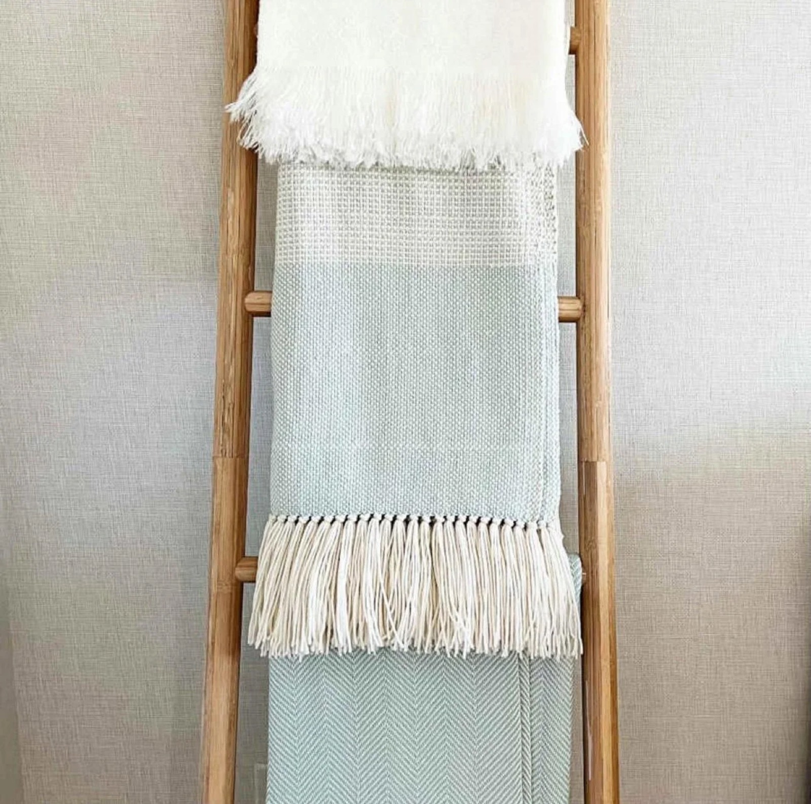 Woven throws layered on a wooden ladder